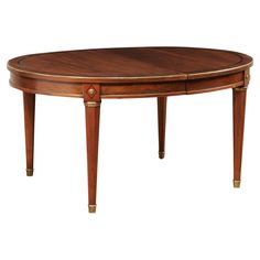 an oval wooden table with gold trimmings on the legs and two leaves at the top