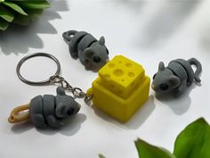 three lego keychains shaped like animals on top of a white table next to green leaves