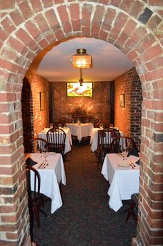 an archway leading into a restaurant with tables set up for dinner and wine glasses on the table