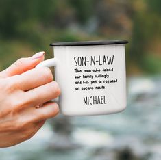 a person holding a coffee mug with the words son - in - law on it