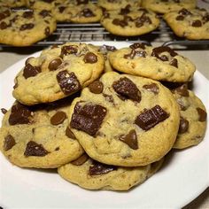 chocolate chip cookies on a white plate with cooling racks in the backgroung