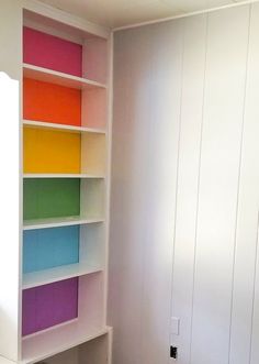 an empty room with white walls and colorful bookshelves