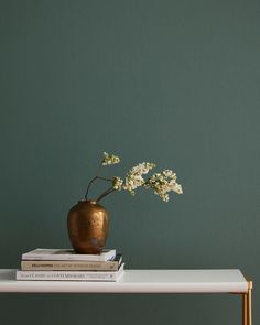 there is a vase with flowers on top of the table next to books and magazines