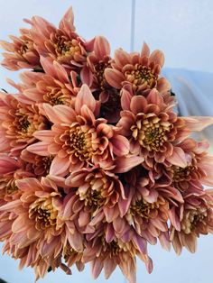 a bunch of pink flowers are in a vase on the table, ready to be used as a centerpiece