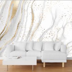 a white couch sitting in front of a wall with gold paint on it