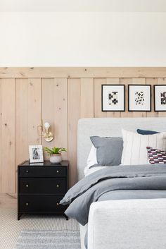 a bedroom with wood paneled walls and white bedding, two framed pictures on the wall