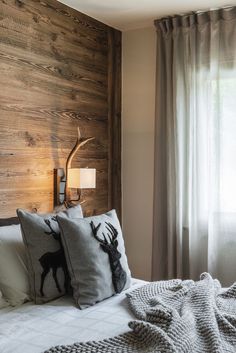 a bed with two pillows on top of it next to a wooden headboard and window