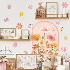 there are many flowers on the wall and pictures in front of them, including daisies