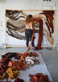 a woman standing in front of a pile of yarn