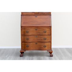 an old wooden dresser sitting on top of a hard wood floor next to a white wall