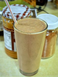 a smoothie with a straw in it sitting on a table next to some jars