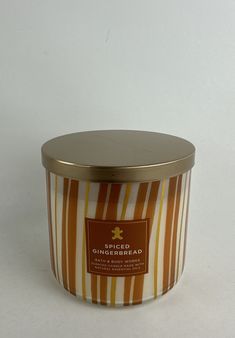 an orange and yellow striped candle with a metal lid on a white tablecloth background