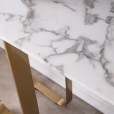 a white marble table with gold legs in a living room or dining room area that is clean and ready for guests to use