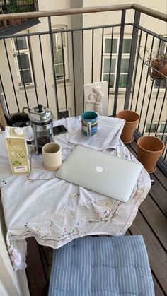 an open laptop computer sitting on top of a white table next to two brown pots