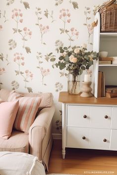 a living room with flowers on the wall and a white couch in front of it