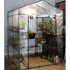 a green house with plastic covering on the roof and plants in pots inside, sitting next to a window