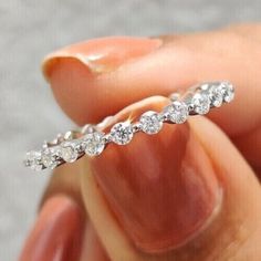 a close up of a person's hand holding a ring with diamonds on it