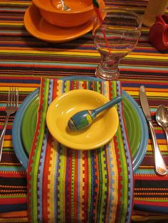 a colorful table setting with place settings and utensils