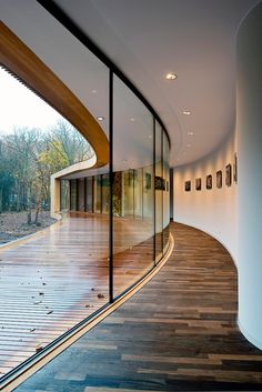 a curved wooden floor with glass walls and pictures on the wall in front of it