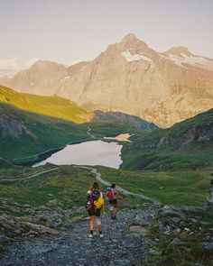 two people walking up a trail in the mountains