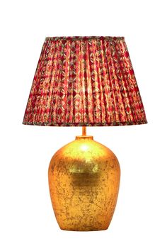 a gold vase with a red lamp shade on the bottom is shown in front of a white background