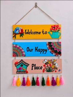 a welcome sign hanging on a wall with some tassels attached to the board