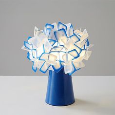 a blue vase filled with white flowers on top of a table next to a gray wall