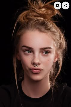 a girl with piercings on her nose looking at the camera while wearing a black shirt