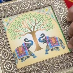 an elephant painting is being displayed in front of a tree with two elephants on it