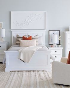 a white bed sitting in a bedroom on top of a hard wood floor next to a chair