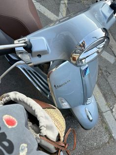 a blue scooter parked on the side of a road next to a bag