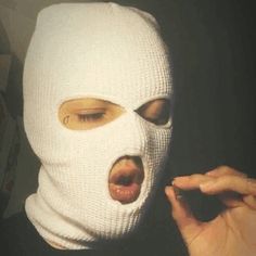 a person wearing a white mask and making a face with their fingers in the air