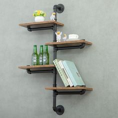 three wooden shelves with metal pipe brackets and books on them, against a gray wall