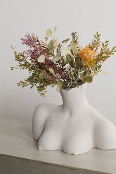 a white vase with flowers in it sitting on a table