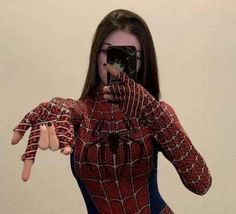 a woman taking a selfie with her cell phone in front of her face, wearing a spider - man costume