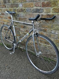 a silver bicycle leaning against a brick wall