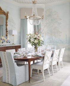 a dining room table with white chairs and flowers in vases on the top shelf