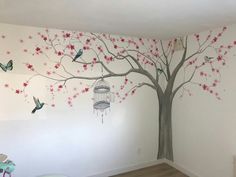 a room with a tree painted on the wall and birds flying in the air next to it