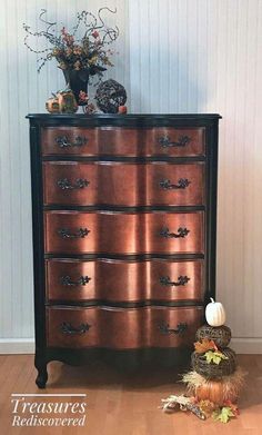 an antique dresser with pumpkins and flowers on top