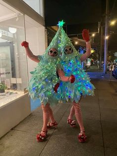 two people dressed up as christmas trees on the sidewalk