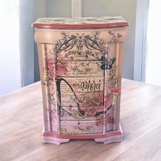 a pink and white painted cabinet sitting on top of a wooden table