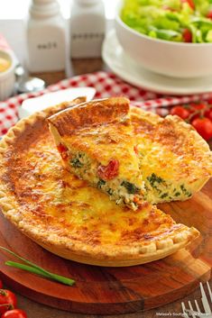 a cheesy quiche on a cutting board with salad in the background