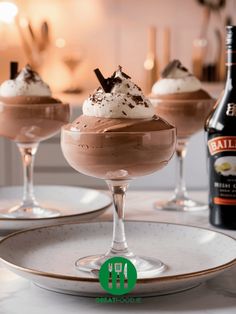 three glasses filled with chocolate desserts on top of a white plate next to a bottle of bailey's irish cream