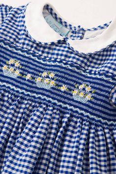 Gingham is always in style for Spring/Summer. It’s the pattern of the season and a delightful choice for picnics in the garden with all the family. The dress has hand embroidered daisies on a sunny blue gingham. Delicate puffed sleeves and a peter pan collar in white gives the dress a signature traditional silhouette. Our dresses are lined in cotton to create a perfect flare for twirling and dancing like everybody’s watching. The Daisy has fabric covered buttons that fasten at the back and an attached sash tie at the waist (12 months+). 100% fine cotton Machine washable at 30°C Traditional hand smocking and embroidery Smocking Dress Patterns, Heirloom Sewing For Babies, Smocking Designs, Smock Pattern, Embroidered Daisies, Baby Dress Embroidery, Hand Smocking, Style For Spring