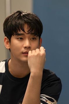 a young man sitting at a table with his hand on his chin and looking off to the side