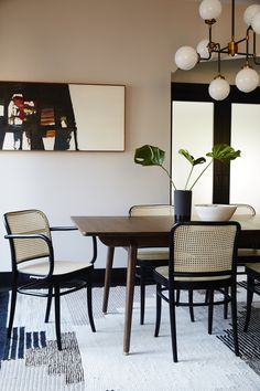 a dining room table with four chairs and a potted plant