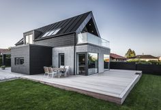 a house with a deck and patio in the grass next to a fenced in yard