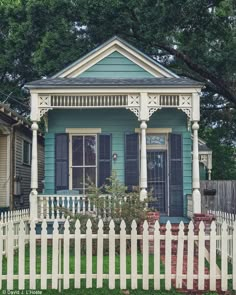 a blue house with white picket fence and trees in the background