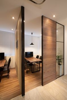 an office with wooden floors and glass partitions to divide the room from the dining area