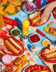 a table full of hot dogs, hamburgers and other condiments on it